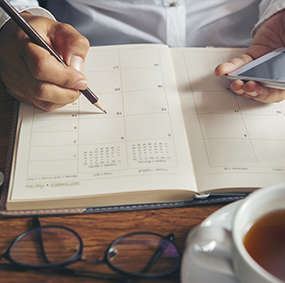 Adult sitting at desk with calendar and phone