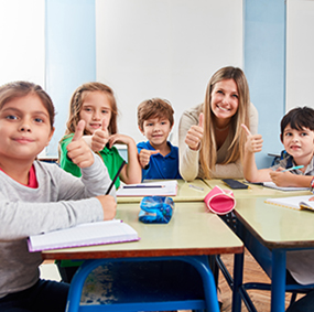 Happy female teacher giving thumbs up with her young students